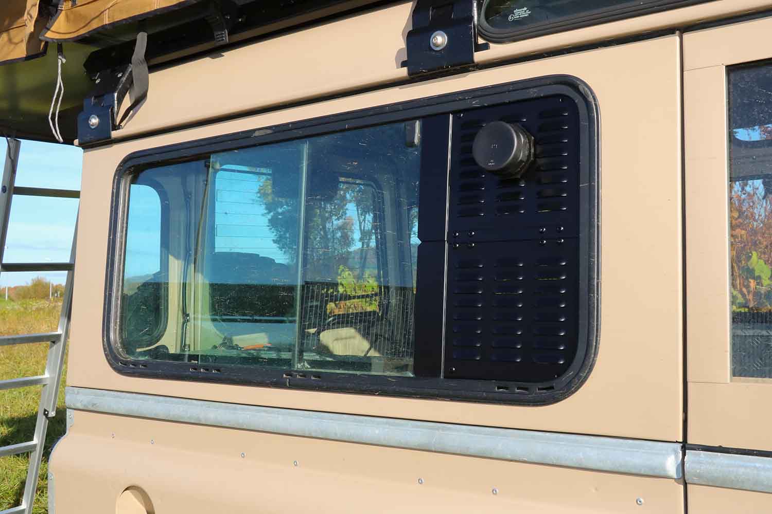 Warmluftdurchführung druch Lüftungsgitter, Ansicht am Defender, hinteres Schiebefenster